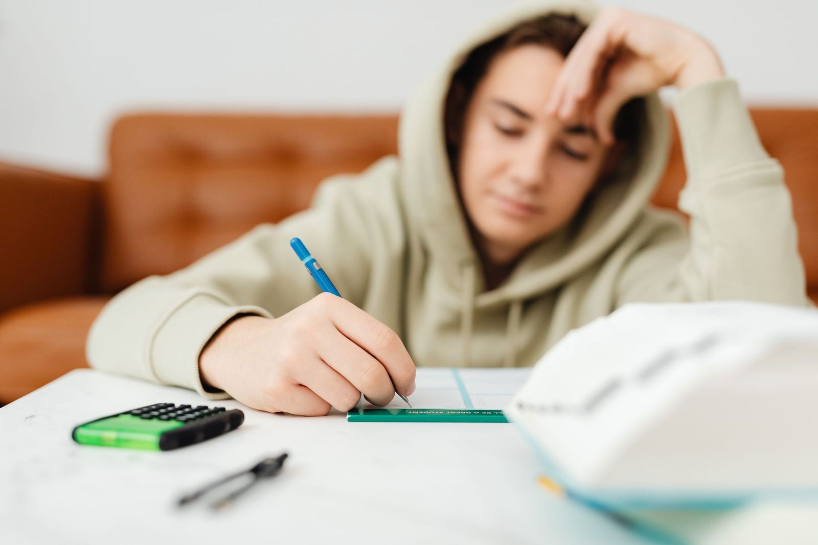 Junger Mensch lernt zu Hause mit Stift und Taschenrechner